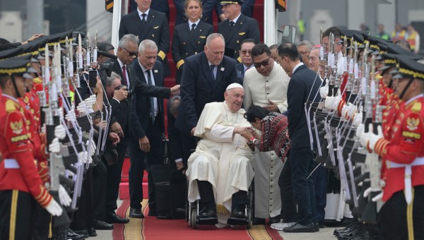 Pope Francis (C, in wheelchair) is welcomed during his arrival at Soekarno-Hatta International Airport in Jakarta on September 3, 2024.
