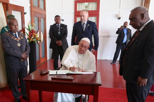 Pope Francis signs the book of honor as he meets with the Papua New Guinea's Governor General Bob Dadae (L) at the Government House in Port Moresby, Papua New Guinea on September 7, 2024.
