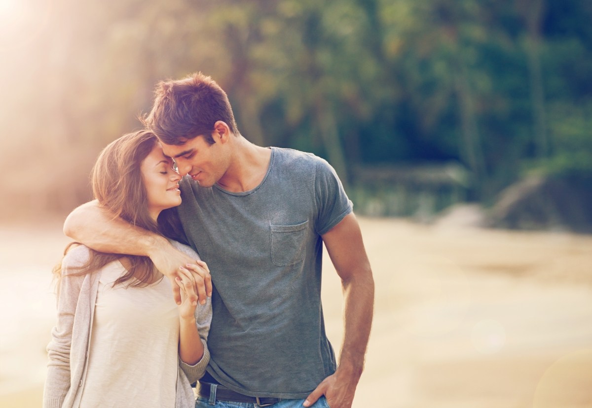 Couple, holding hands and hug on beach date in outdoors, love and bonding in relationship on vacation