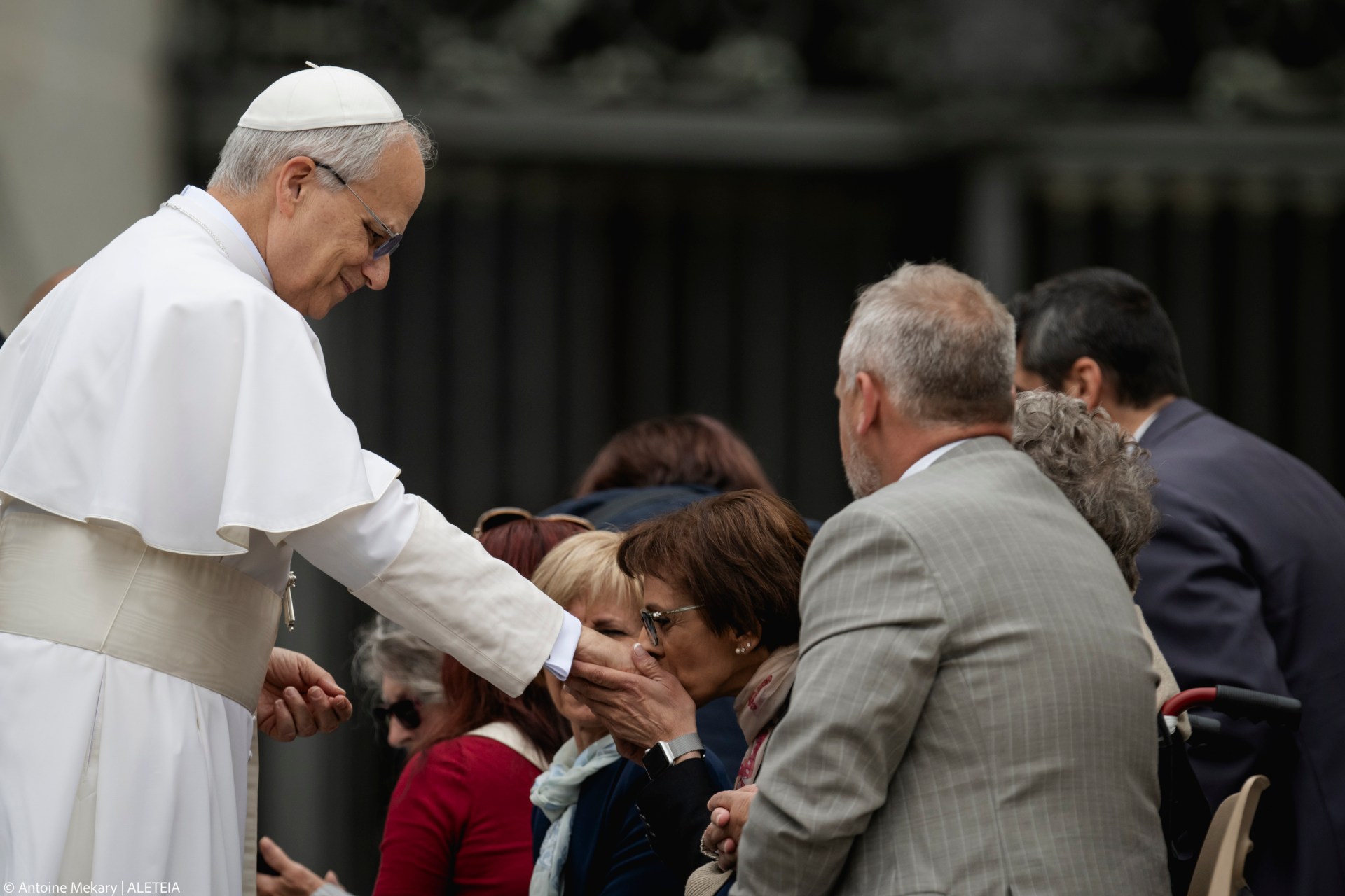 A woman kisses the hand Pope Leo XIV at the end of his first weekly general audience at St Peter's Square in The Vatican on May 21, 2025