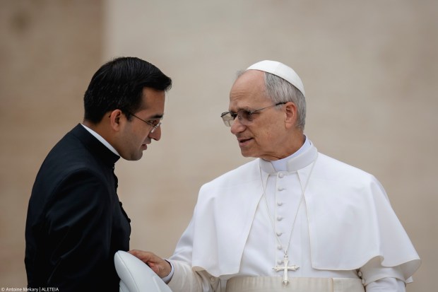 Papa Leone XIV parla al suo assistente personale Edgard Ivan Rimaycuna Inga alla fine della sua prima udienza generale settimanale a Piazza San Pietro in Vaticano il 21 maggio 2025.