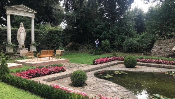 A statue of Mary presides over a clearing with a man-made pond at Borgo Laudati si' in Castel Gandolfo.