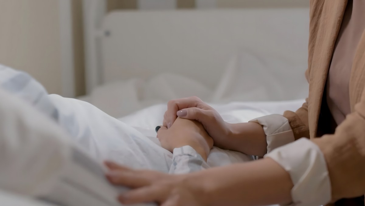 holding a hand titely on hospital bed