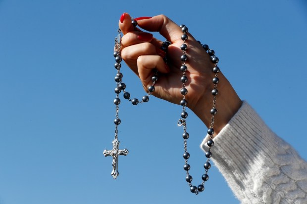 woman-hand-rosary-blue-sky