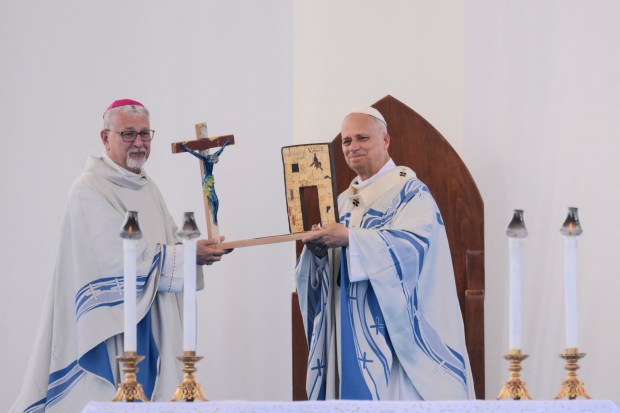 Agrigento's Archibishop Alessandro Damiano (L) gives a miniature of the monument Door of Europe - Porta d'Europa to Pope Leo XIV (R) at the end of the mass during a one day visit to Lampedusa island, south of Sicily, on July 4, 2026.